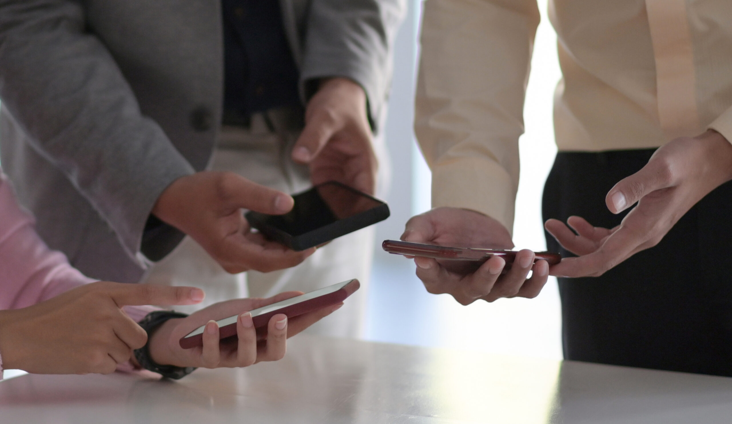 עובדים רבים מחזיקים את הסמארטפונים שלהם אחד ליד השני כדי לשלוח הודעות SMS